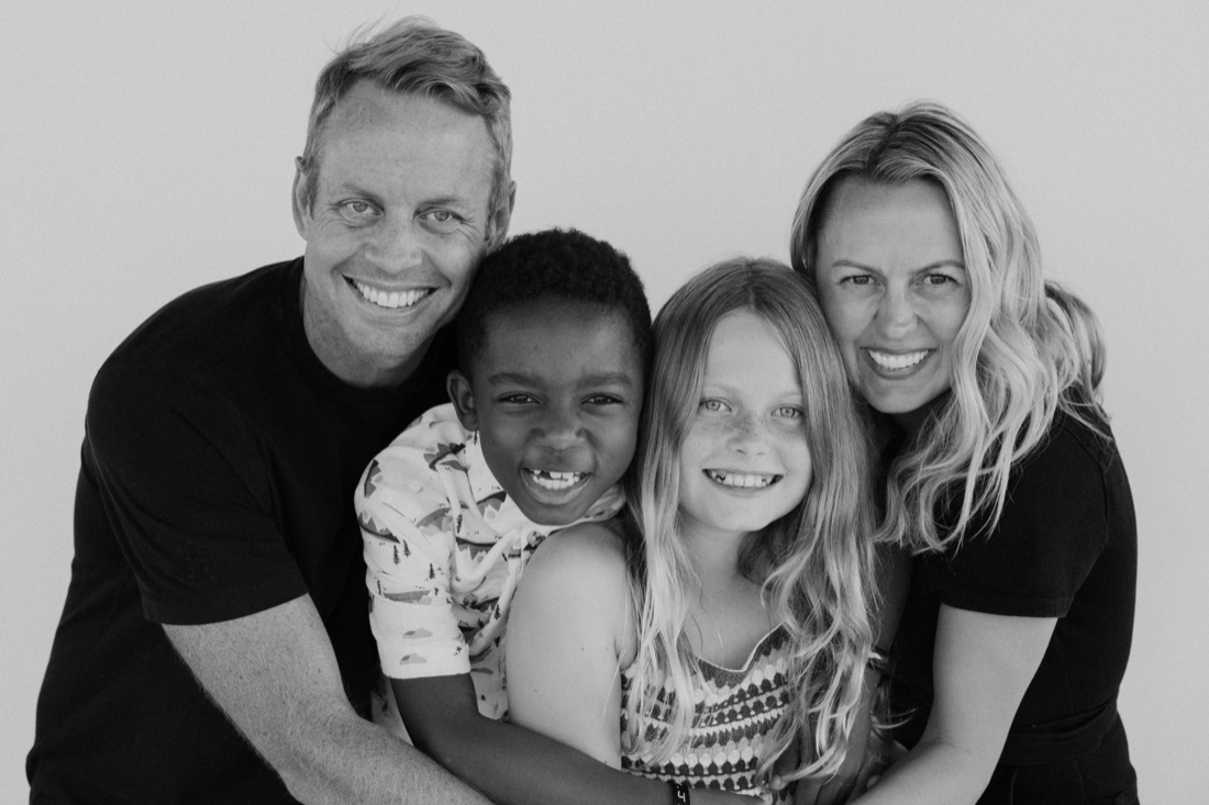 A family of four hugging and smiling, photographed at last year's Fall Photo Event